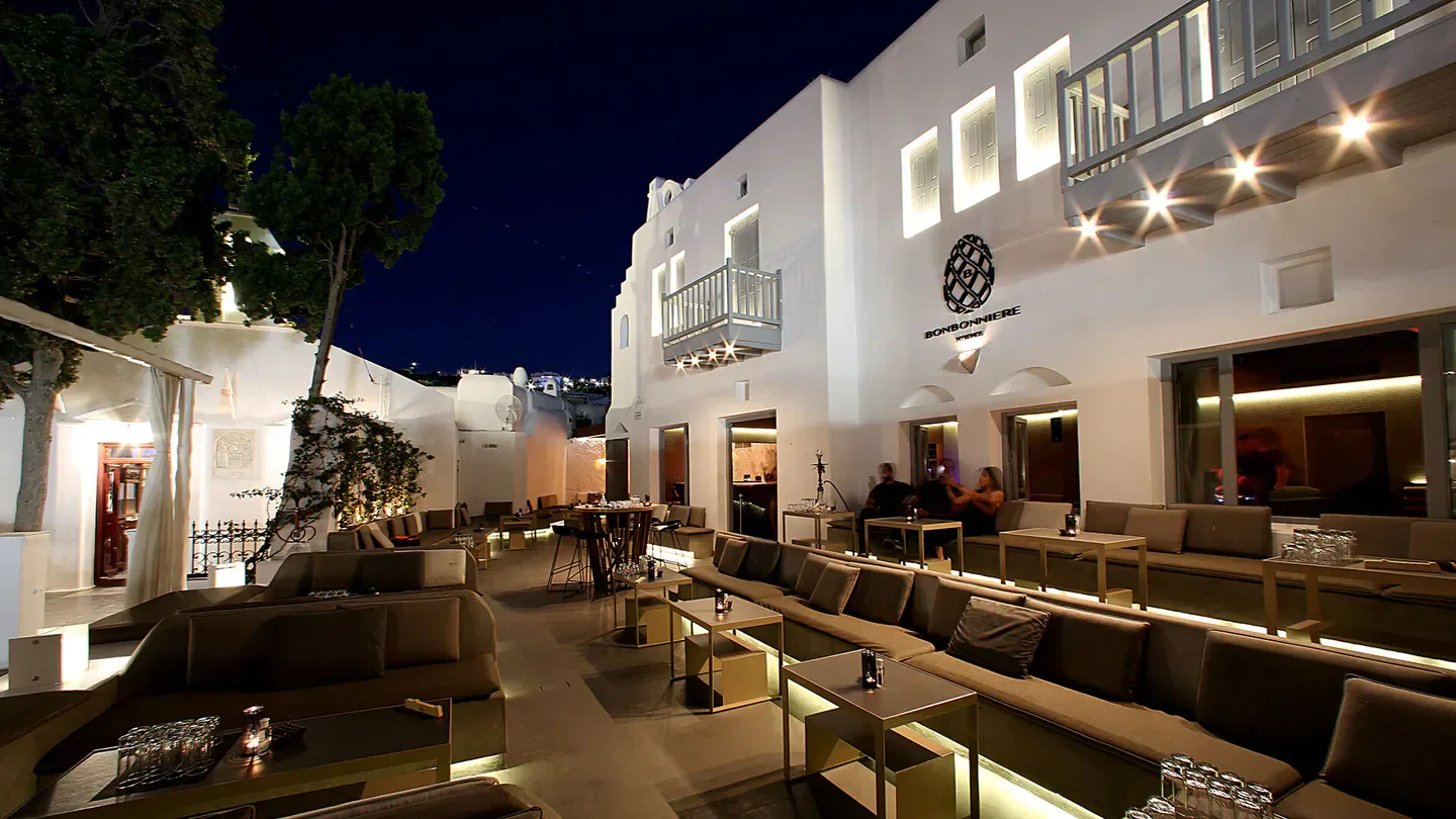 Outdoor seating at Bonbonniere nightclub in Mykonos at night, with stylish decor.