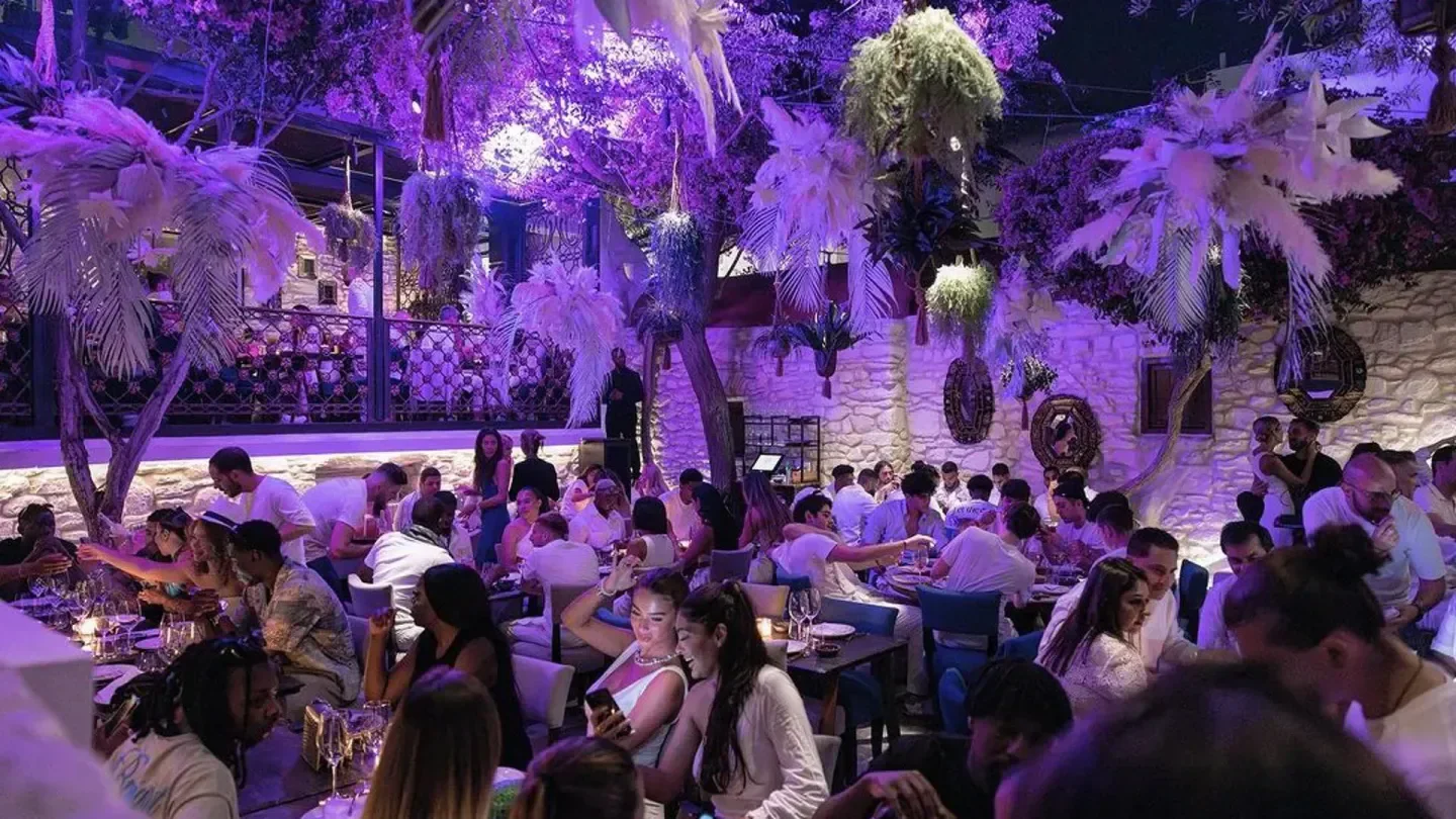 Coya Mykonos: Stylish restaurant interior, filled with people, illuminated by purple lighting