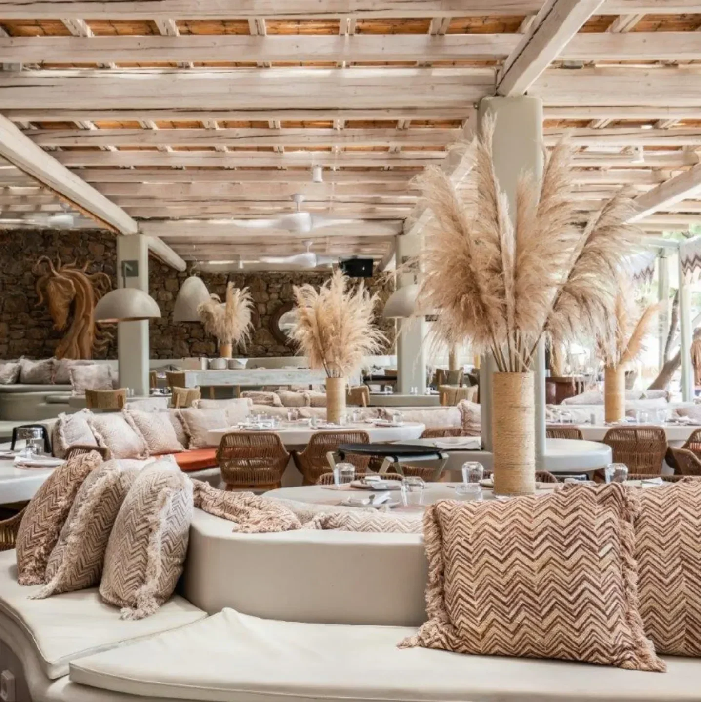 Cozy seating at Kalua Beach Bar in Mykonos, featuring decorative pillows and dried flowers.