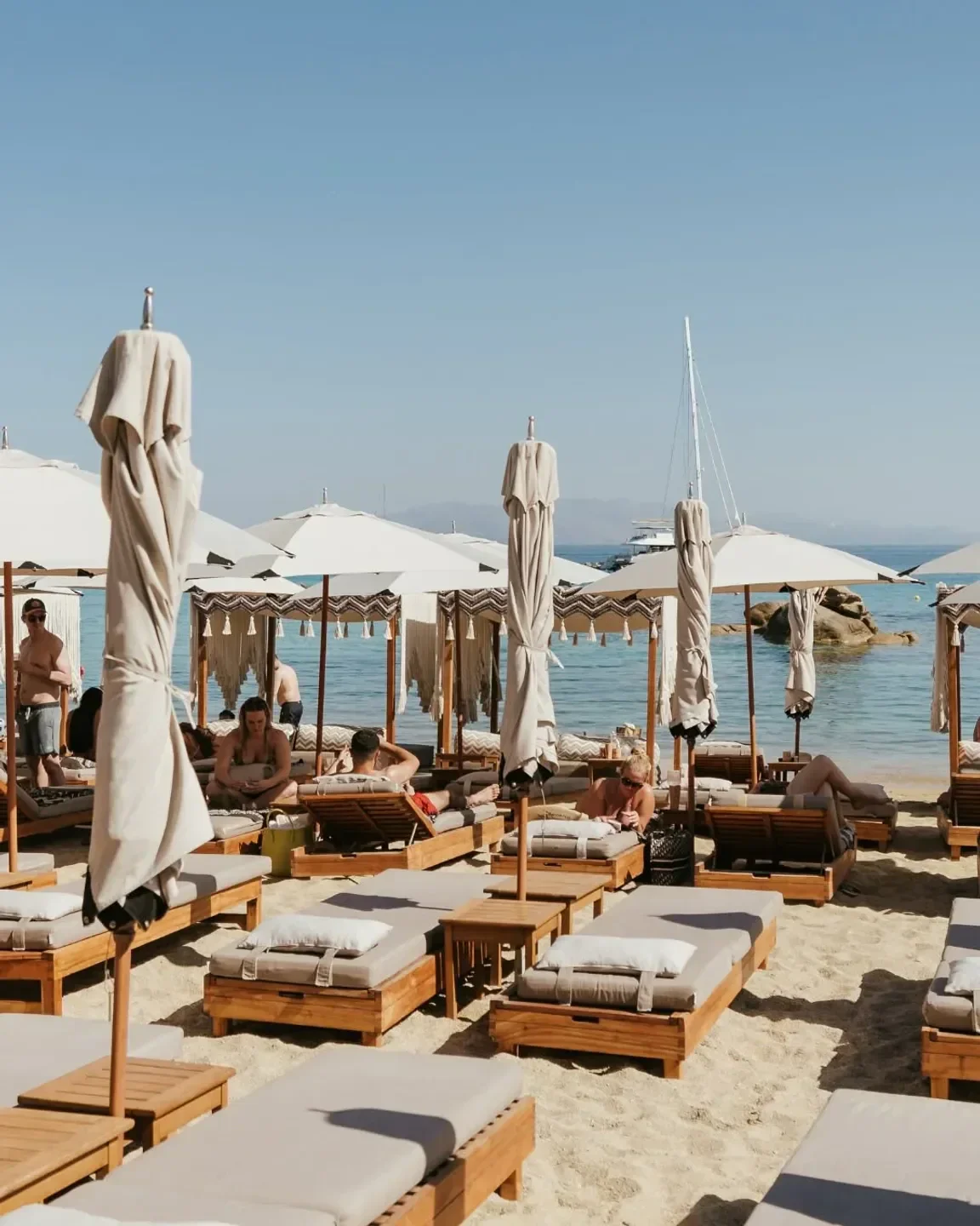 Beach scene at Kalua Beach Bar in Mykonos, with sunbeds and umbrellas.