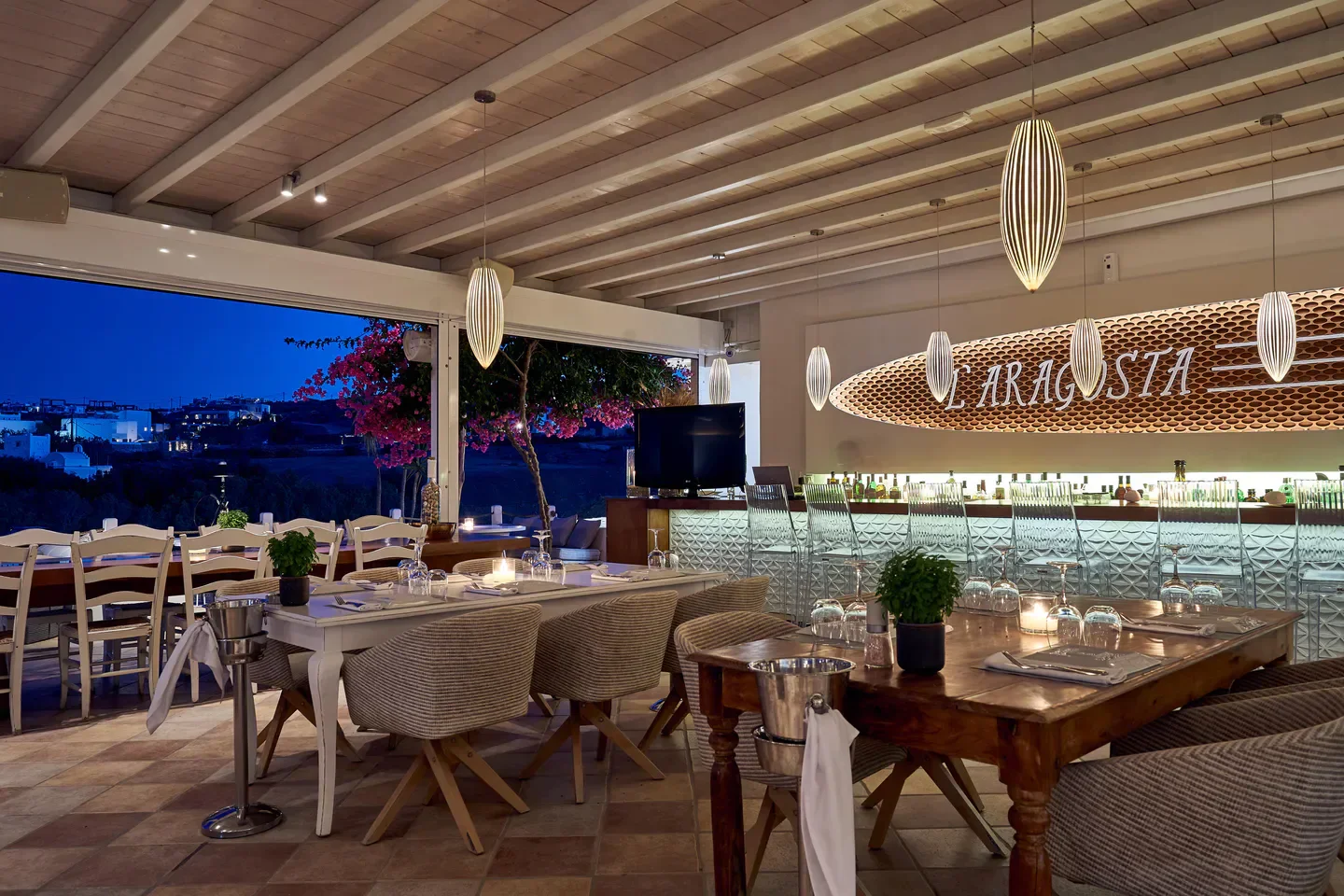 Elegant dining at L'Aragosta restaurant in Mykonos, featuring stylish decor and open-air views.