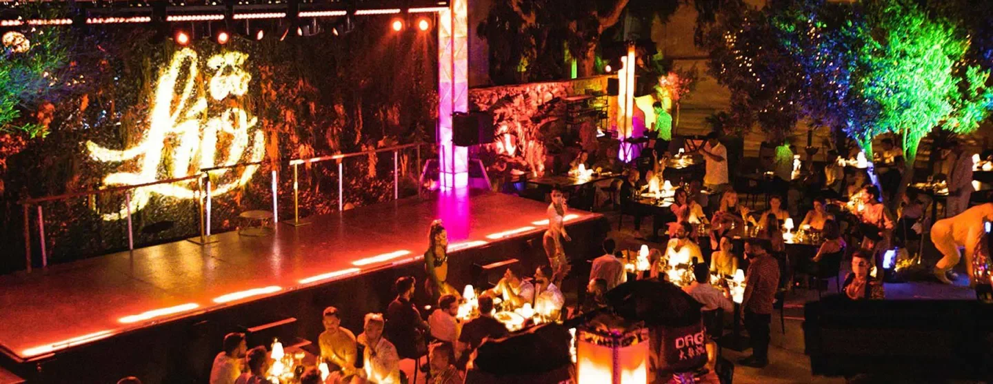 Elegant dining experience at Lio Mykonos, featuring a stage for performances and vibrant ambiance.