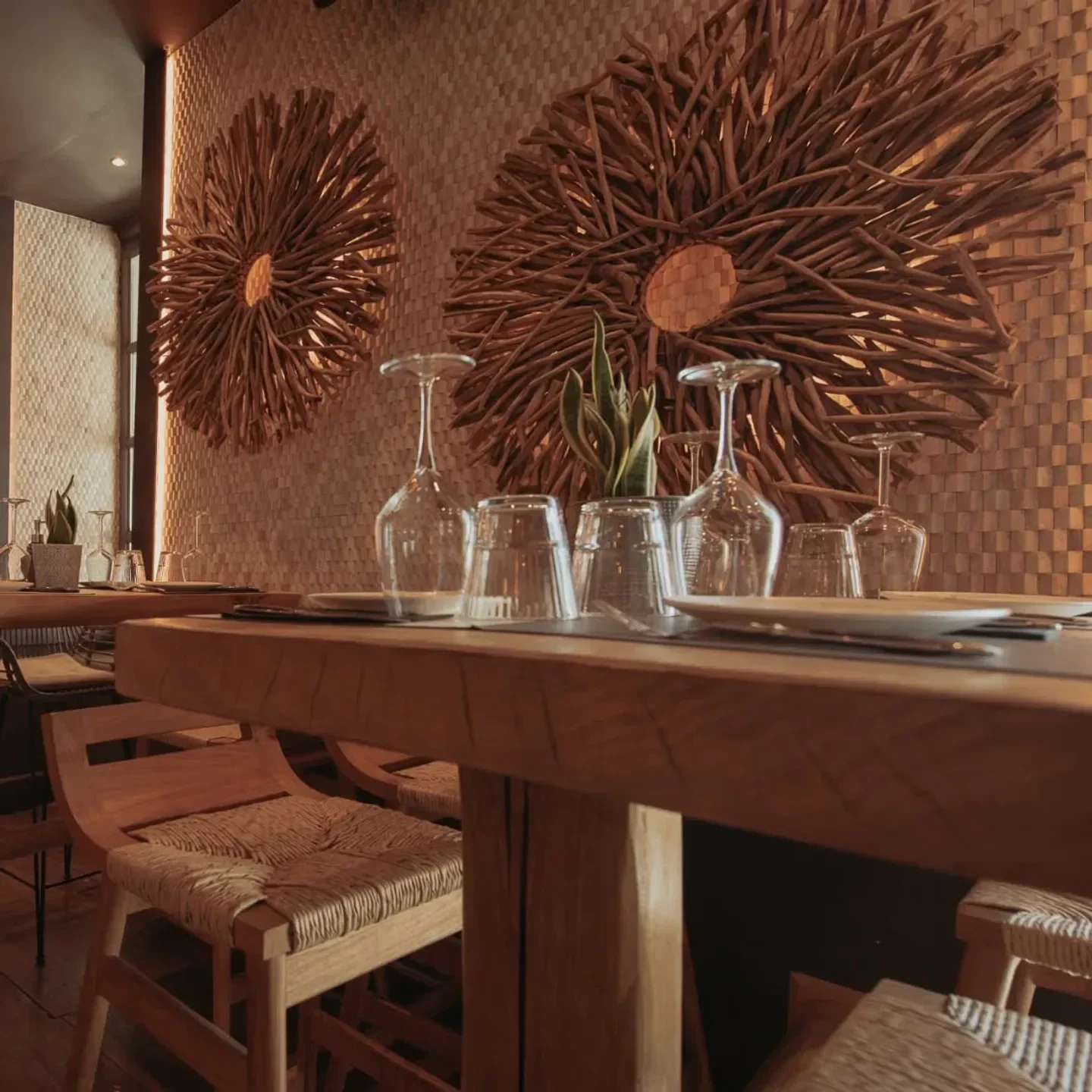 Interior of Mosaic of Mykonos restaurant with wooden tables and artistic wall decor.