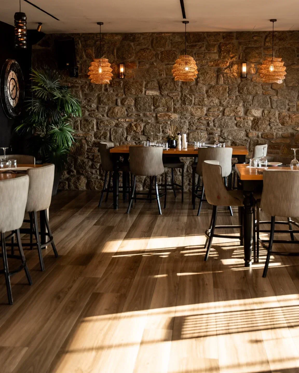 Cozy dining area at Obati restaurant in Mykonos, featuring stone wall and wooden tables