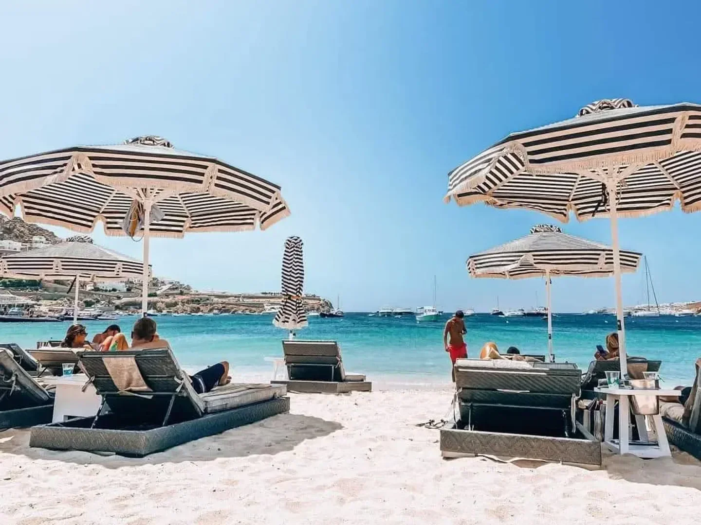 Beach scene at Pasaji in Mykonos with striped umbrellas and ocean views