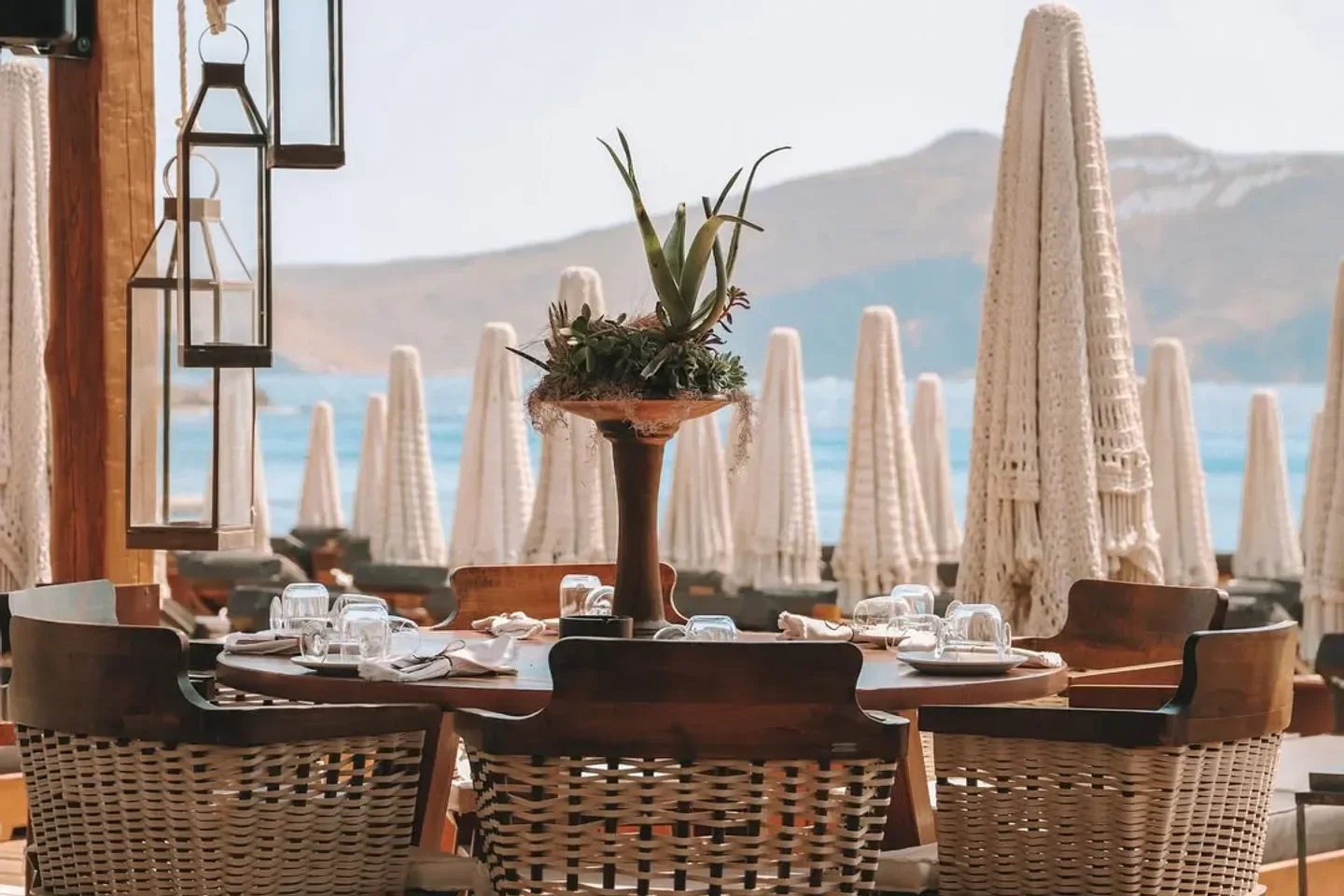 Dining setup at Principote Beach Club in Mykonos, with beach umbrellas in the background