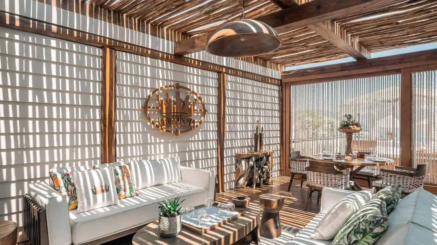 Stylish lounge area at Principote Beach Club in Mykonos, with shadow play and seating.