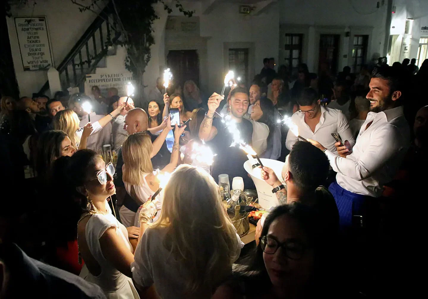 Queen Mykonos nightlife with sparklers and crowd celebrating in the nightclub.