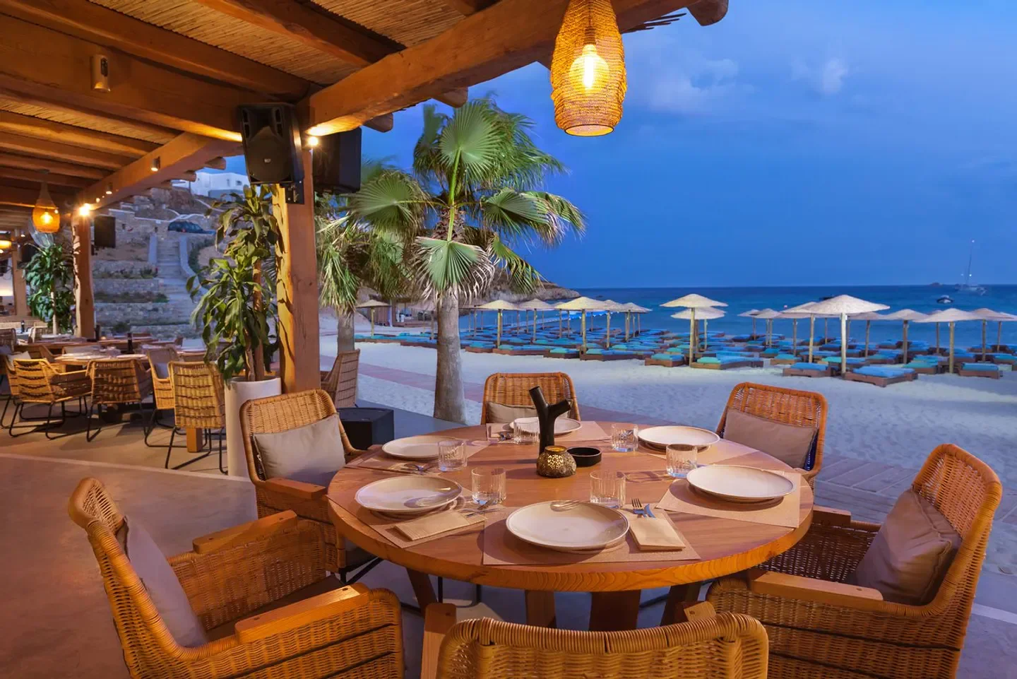 Beachfront dining at Solymar Mykonos, with views of the Aegean Sea at dusk.