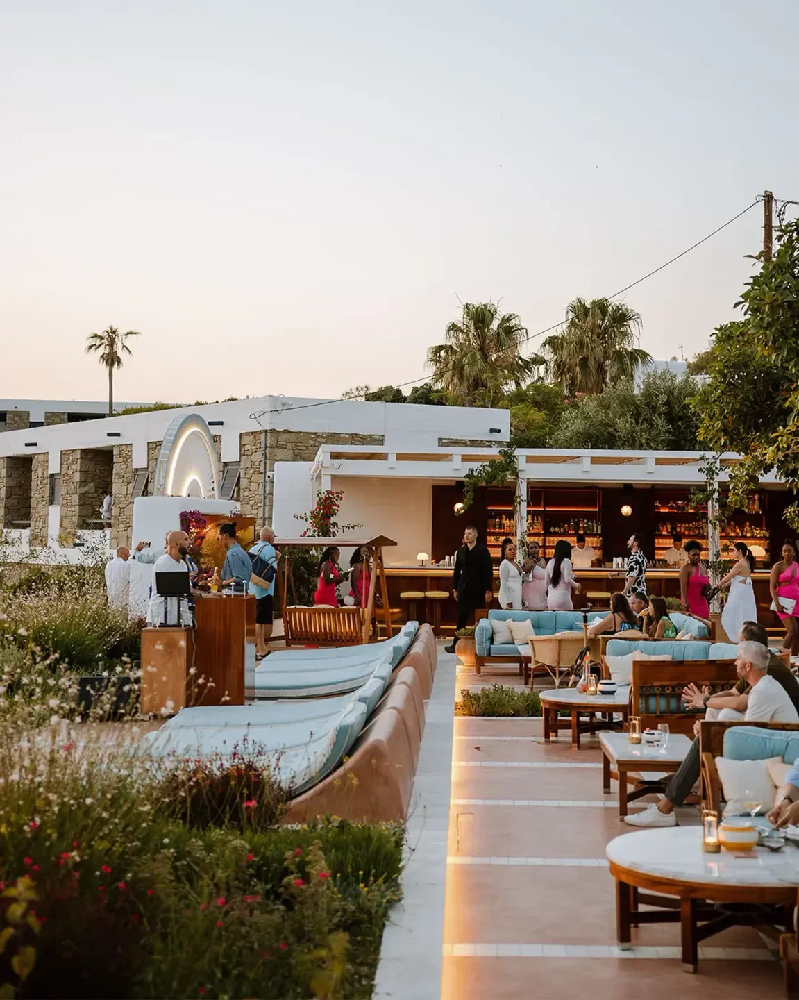 Outdoor seating at Sunset Plaza restaurant in Mykonos, Greece, with people enjoying the ambiance.