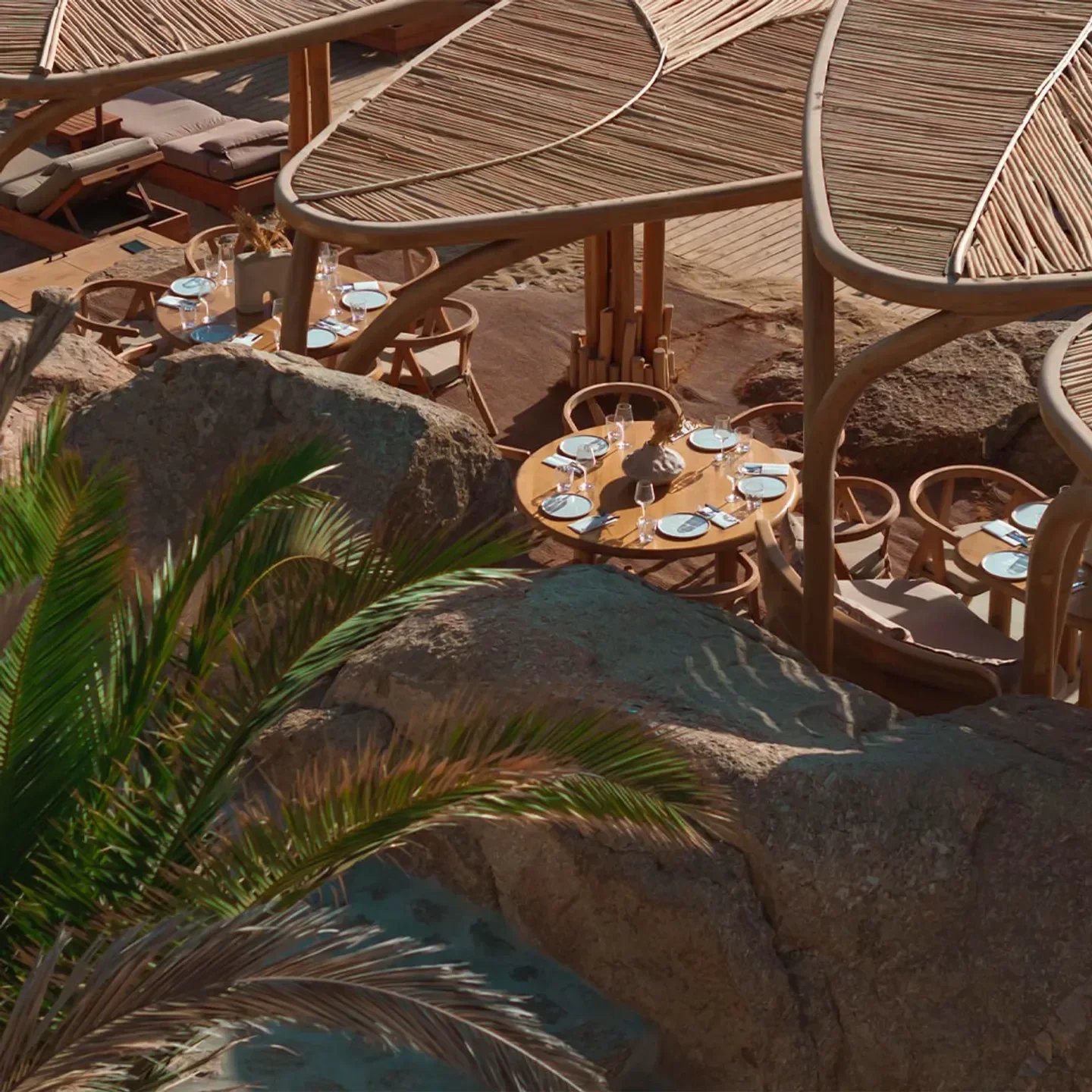 Restaurant seating at Super Paradise in Mykonos, shaded by natural wood structures.
